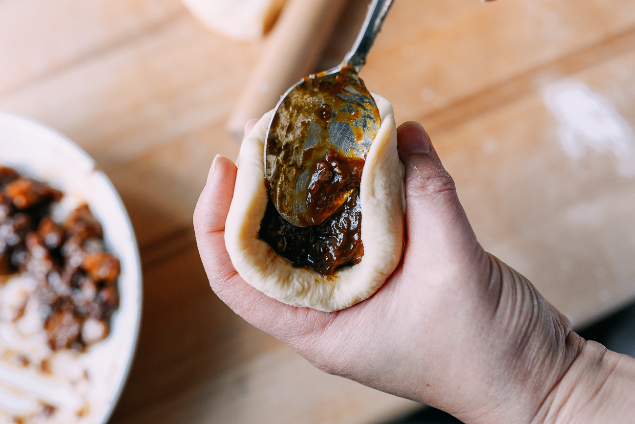 Using a spoon to press filling into dough