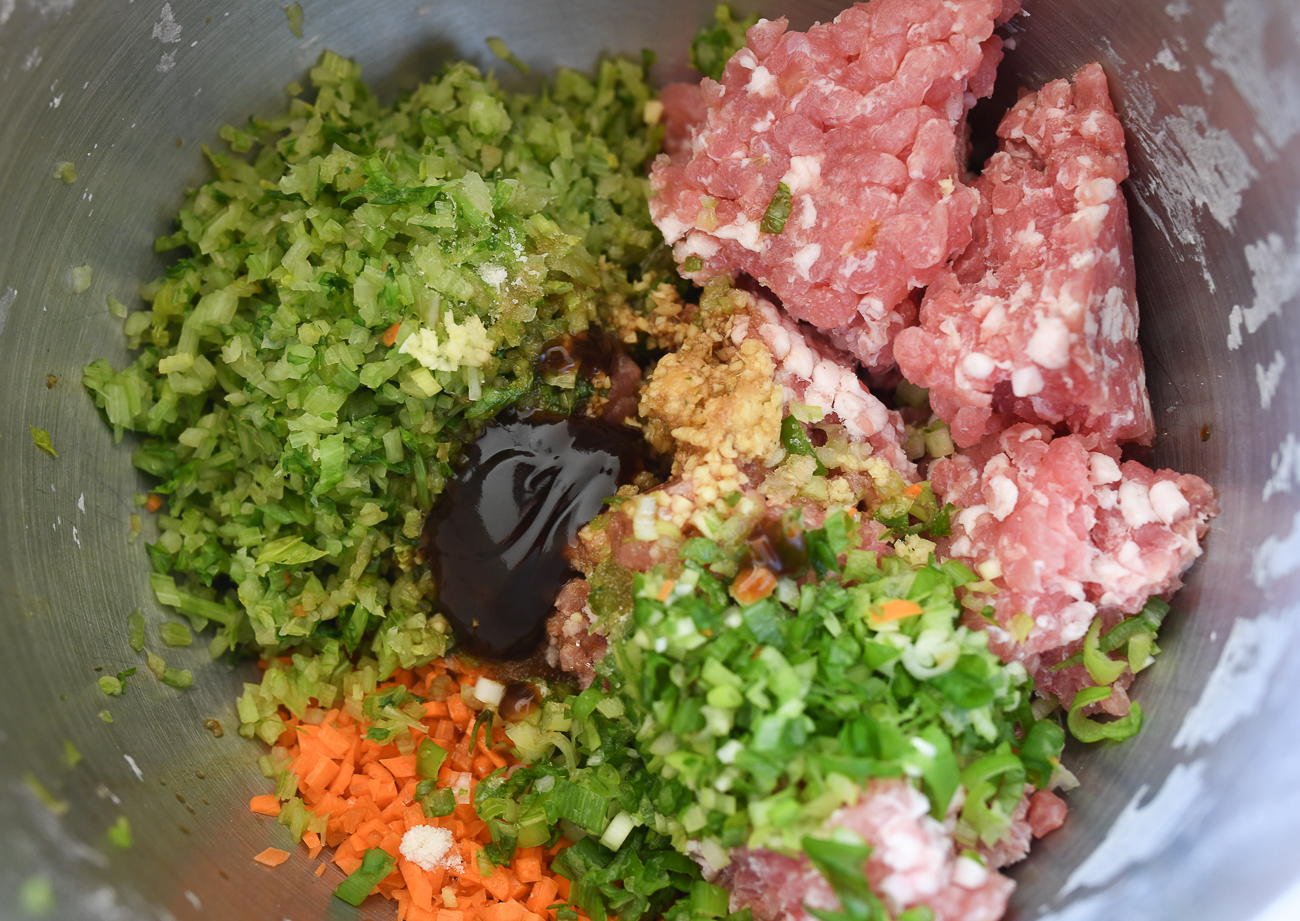 Pork and celery dumpling filling ingredients in stainless steel mixing bowl